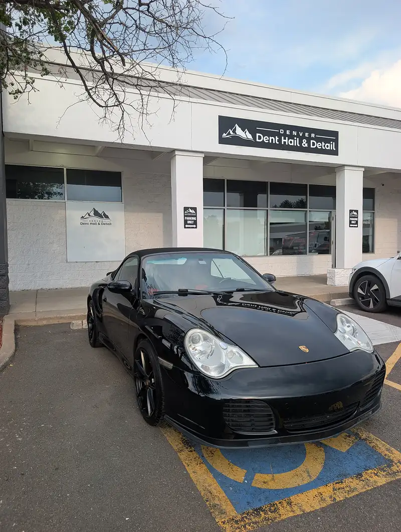 Black Porsche 911 parked outside the storefront at Dent, Hail & Detail in Denver